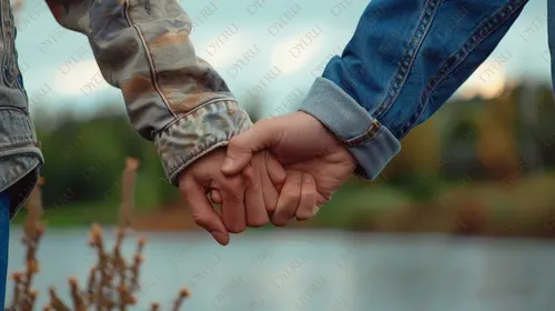 أيدٍ متشابكة لشريكين في لحظة رومانسية بالقرب من الماء