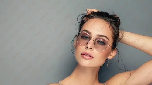 امرأة شابة أنيقة ترتدي نظارات شمسية مع تسريحة شعر عصرية وخلفية رمادية